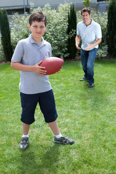 Little boy and father playing american football - Fotó, kép