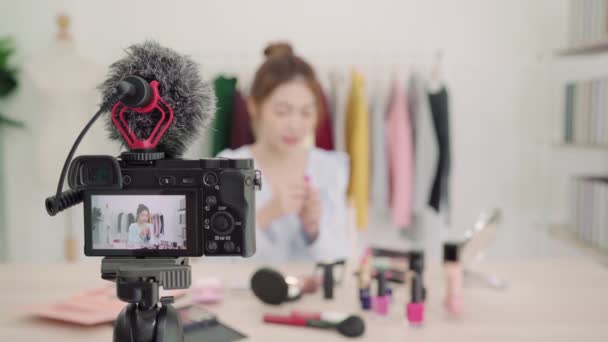 美容ブロガーは、ビデオ録画のためのカメラの前に座って美容化粧品を紹介します。美しいアジアの女性は、チュートリアルをレビュー作るインターネットの社会的ネットワークに放送中にブラシを使用してください。. - 映像、動画