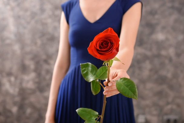 Woman with beautiful red rose against dark background - Photo, Image