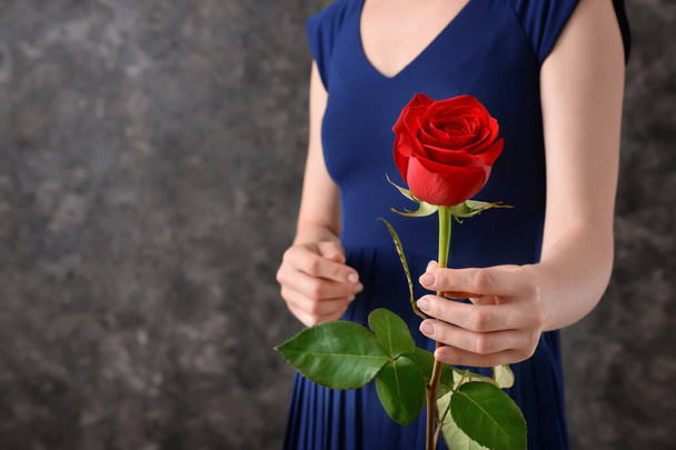 Woman with beautiful red rose against dark background - Fotoğraf, Görsel