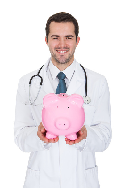 Young Female Doctor Holding Piggy Bank - Foto, immagini