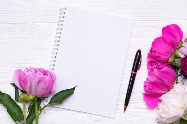Lege laptop met plek voor tekst en pioenrozen bloemen op een witte achtergrond - Foto, afbeelding