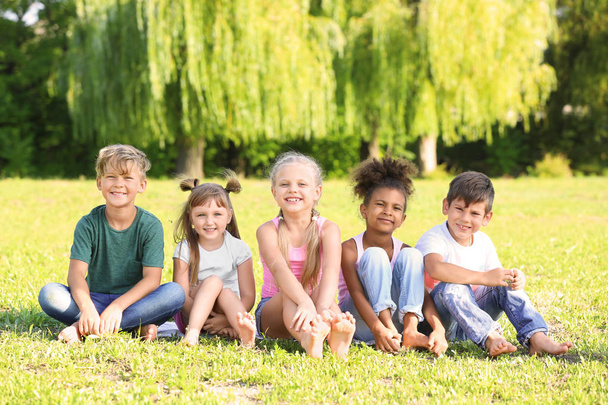 Leuke lieve kinderen zitten op gras buitenshuis - Foto, afbeelding