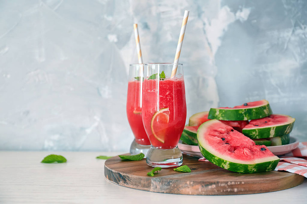 Glasses with fresh smoothie and watermelon slices on wooden board - Valokuva, kuva