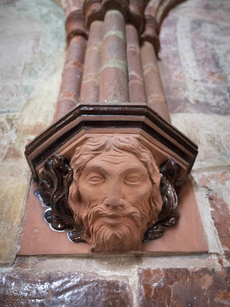 Detail keramické pilastr kapitálu zdobí dekorativní mužova hlava (křižácký hrad Malbork, Polsko v létě 2018) - Fotografie, Obrázek