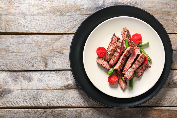 Assiette avec steak grillé coupé et légumes sur table en bois
 - Photo, image