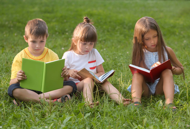 Χαριτωμένα παιδάκια διαβάζοντας βιβλία στο πάρκο θερινή ημέρα - Φωτογραφία, εικόνα
