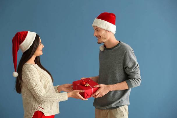 Linda pareja joven con regalo de Navidad en el fondo de color
 - Foto, Imagen