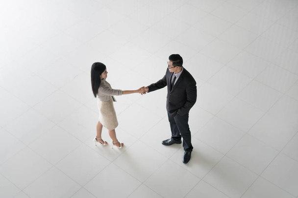 Vista superior del empresario asiático y la mujer de negocios estrechando la mano en el vestíbulo de la oficina. Bienvenido a los negocios
 - Foto, imagen