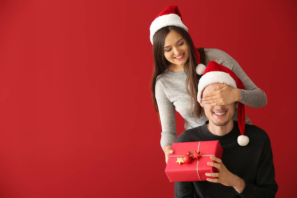 Молодой человек получает рождественский подарок от жены на цветном фоне
 - Фото, изображение