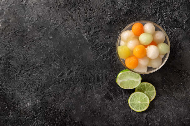 Bol avec de délicieuses boules de melon et citron vert sur la table de grunge
 - Photo, image