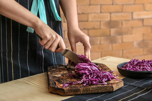 Woman cutting fresh red cabbage at table - Photo, Image