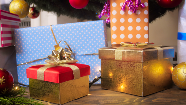Closeup 4k πλάνα του στολίδια, γιρλάντες λαμπερό και δώρο κουτιά κάτω από το χριστουγεννιάτικο δέντρο στο σαλόνι - Πλάνα, βίντεο