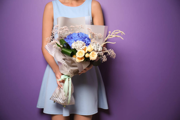Young woman holding bouquet of beautiful flowers on color background - Fotografie, Obrázek