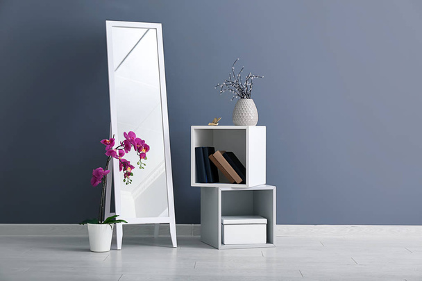 Велике дзеркало з меблями біля кольорової стіни в кімнаті
 - Фото, зображення