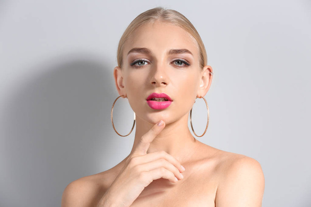 Hermosa mujer joven con lápiz labial de color rosa brillante sobre fondo claro
 - Foto, imagen
