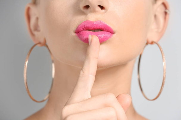 Hermosa mujer joven con lápiz labial de color rosa brillante sobre fondo claro, primer plano
 - Foto, imagen