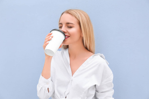 Mulher bonita com xícara de café perto da parede de cor
 - Foto, Imagem
