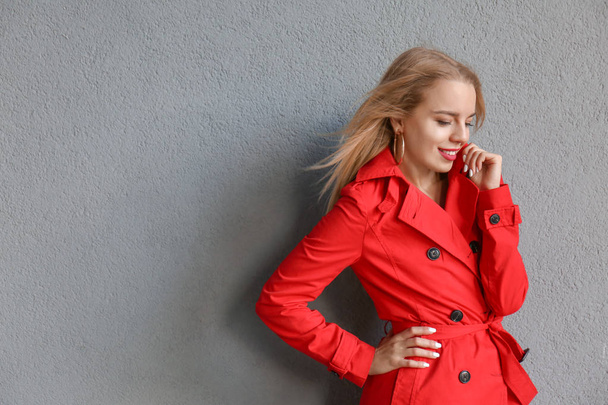 Hermosa mujer joven con elegante abrigo rojo cerca de la pared de color
 - Foto, Imagen