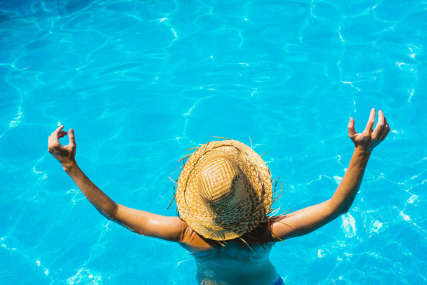 Vrouw in een pool met hoed ontspannen en uitgerust. - Foto, afbeelding