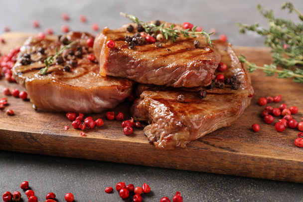 Délicieux steaks grillés aux épices sur planche de bois
 - Photo, image