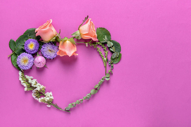 Heart made of beautiful flowers and leaves on color background - Photo, image