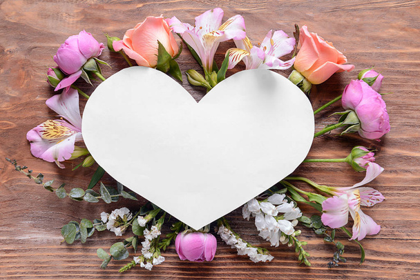 Foglio di carta a forma di cuore con bellissimi fiori su sfondo di legno
 - Foto, immagini