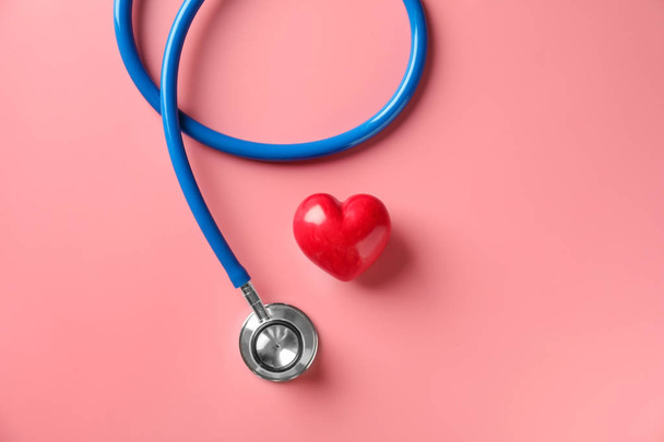 Medical stethoscope and red heart on color background. Cardiology concept - Photo, Image