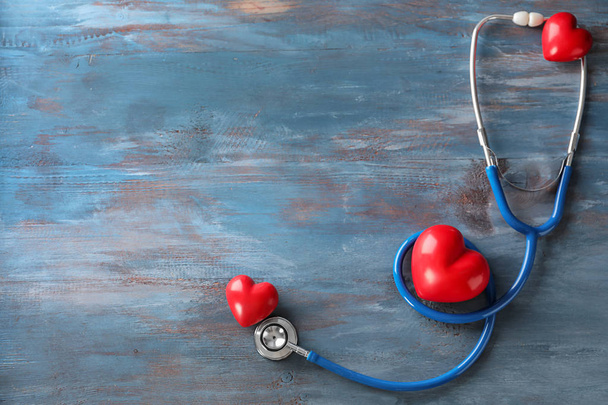 Medical stethoscope and red hearts  on wooden background. Cardiology concept - Photo, Image