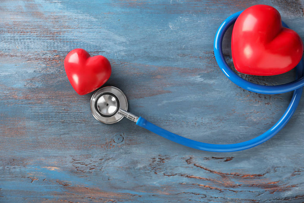 Medyczny stetoskop i czerwone serca na tle drewnianych. Kardiologia koncepcja - Zdjęcie, obraz