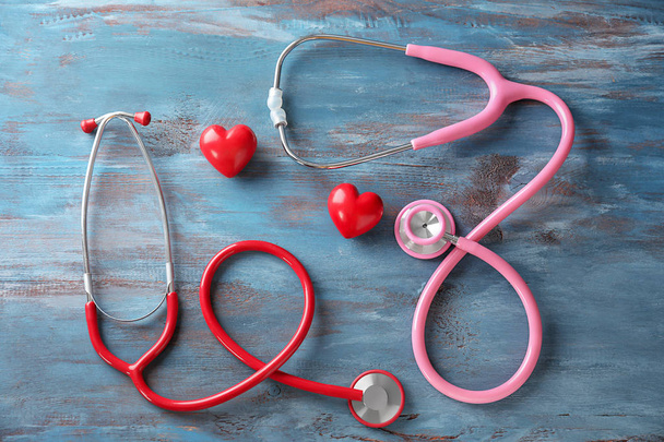 Medical stethoscopes and red hearts  on wooden background. Cardiology concept - Photo, Image