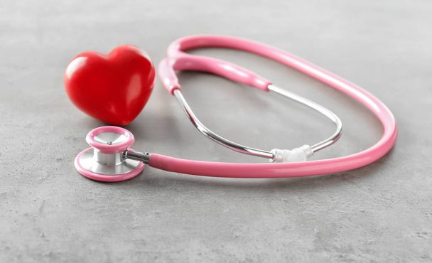 Estetoscopio médico y corazón rojo sobre mesa gris. Concepto de cardiología
 - Foto, Imagen