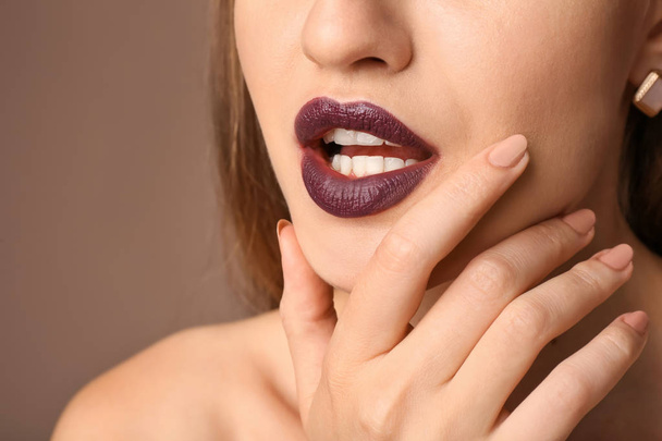 Beautiful young woman with dark lipstick on color background, closeup - Fotó, kép