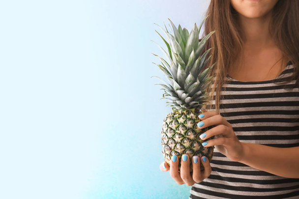 Woman with professional manicure holding delicious pineapple on light background - Photo, Image