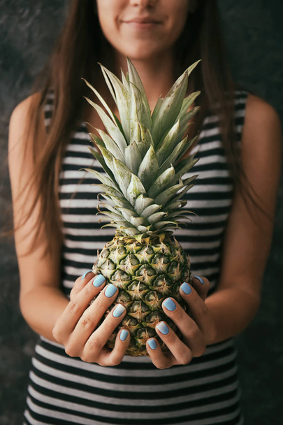 Woman with professional manicure holding delicious pineapple on grey background - Zdjęcie, obraz