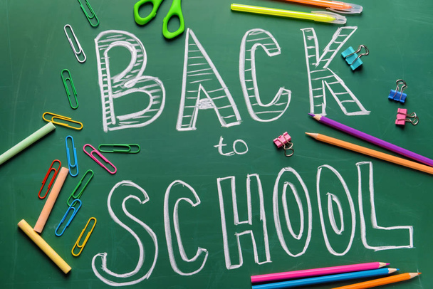 Stationery and words BACK TO SCHOOL written on chalkboard - Photo, Image