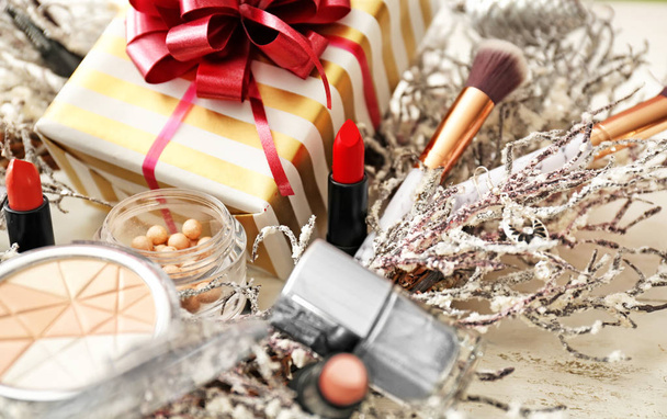 Set of decorative cosmetics with Christmas present and wreath on white wooden table - Photo, Image