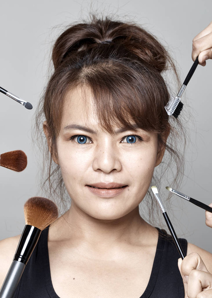 Азіатський молодих красива жінка, застосовуючи косметичних порошок пензля на обличчя білим фоном. - Фото, зображення