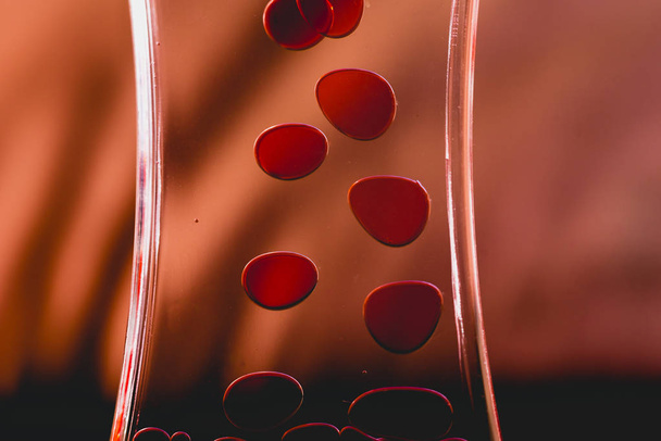 Red drops similar to blood falling in water. - Foto, afbeelding