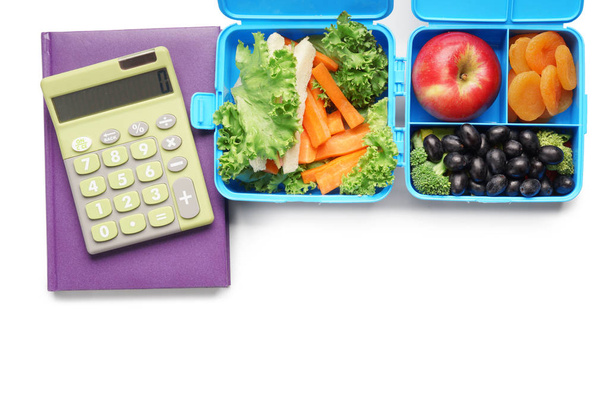 Comida para escolares en loncheras y calculadora sobre fondo blanco
 - Foto, imagen