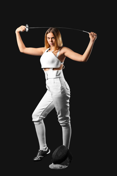 Young female fencer on dark background - Фото, изображение