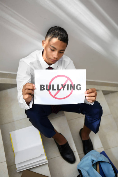 Un adolescent afro-américain tenant une feuille de papier avec le mot BULLYING à l'école
 - Photo, image