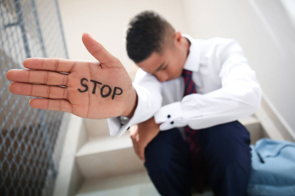 学校で階段の上に座って手に書かれた stop とアフリカ系アメリカ人の 10 代の少年 - 写真・画像