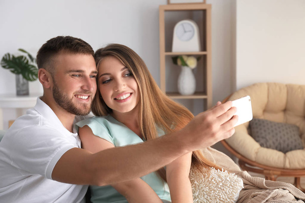 Feliz pareja amorosa tomando selfie en casa
 - Foto, imagen