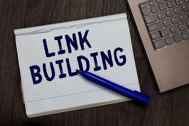 Conceptual hand writing showing Link Building. Business photo text SEO Term Exchange Links Acquire Hyperlinks Indexed Open notebook squared page black marker computer wooden background. - Photo, Image