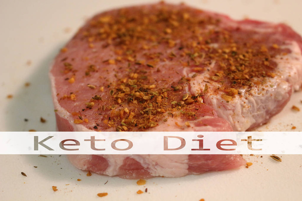 Raw meat with the words keto diet in transparent text on it. This is pork. In recent news the keto diet has received negative reviews. - Photo, Image