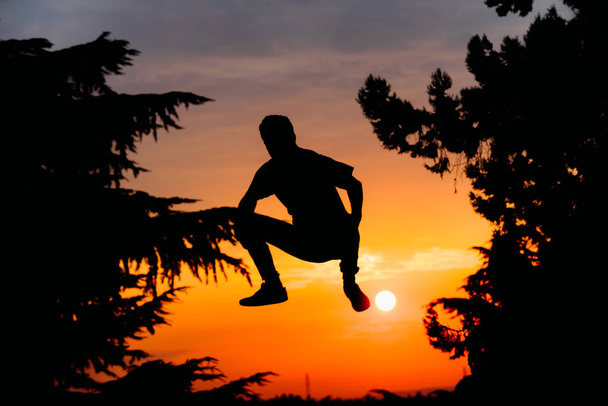 Паркур людина під час стрибків у міському парку на заході сонця
 - Фото, зображення