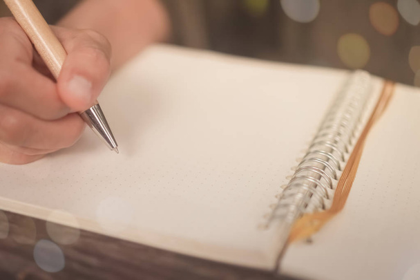 Χώρο αντίγραφο της γυναίκας χέρι γράφοντας κάτω σε άσπρο σημειωματάριο με ήλιος ανοιχτόχρωμο φόντο.  - Φωτογραφία, εικόνα