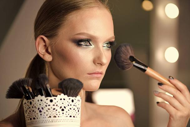 Beautiful woman face powder, and apply blush to cheekbones - Fotoğraf, Görsel