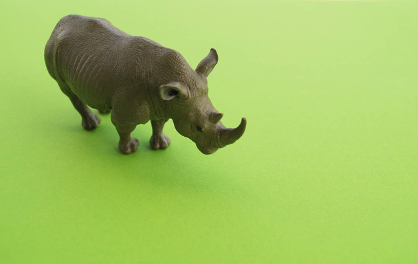 An rhinoceros animal is a children's toy. Plastic figurine for the game. Green background. Farm and the zoo. - Φωτογραφία, εικόνα